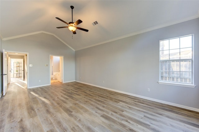 spare room with light wood-style flooring, visible vents, baseboards, vaulted ceiling, and ornamental molding