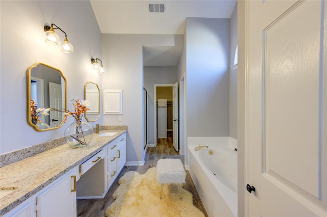 full bathroom featuring double vanity, a jetted tub, a sink, and visible vents