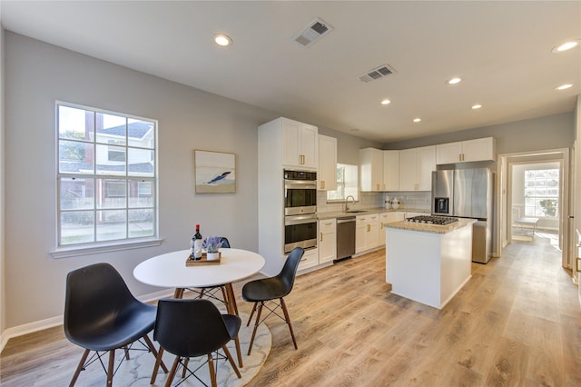 kitchen with light wood-type flooring, visible vents, appliances with stainless steel finishes, and tasteful backsplash