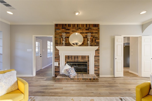 living room featuring baseboards, a fireplace, visible vents, and ornamental molding