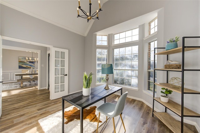 office space featuring baseboards, high vaulted ceiling, wood finished floors, and a notable chandelier