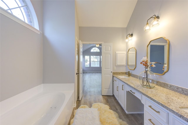 full bath featuring wood finished floors, a garden tub, a sink, and double vanity