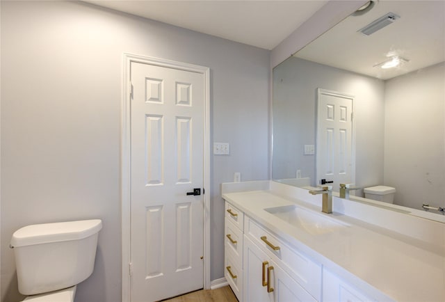 bathroom featuring visible vents, vanity, and toilet