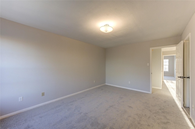 empty room featuring light carpet and baseboards