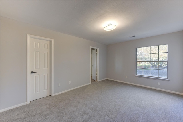 carpeted empty room featuring baseboards and visible vents