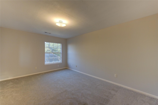 unfurnished room featuring carpet, visible vents, and baseboards