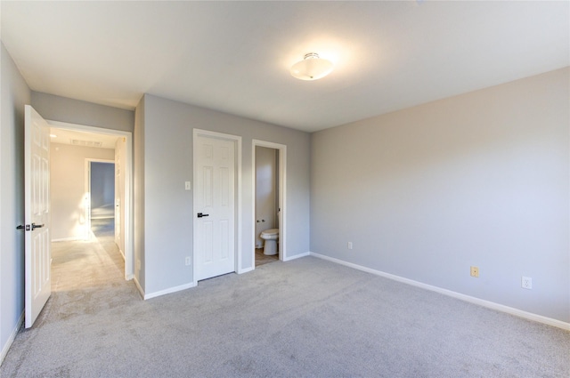 unfurnished bedroom featuring light carpet, baseboards, and ensuite bathroom