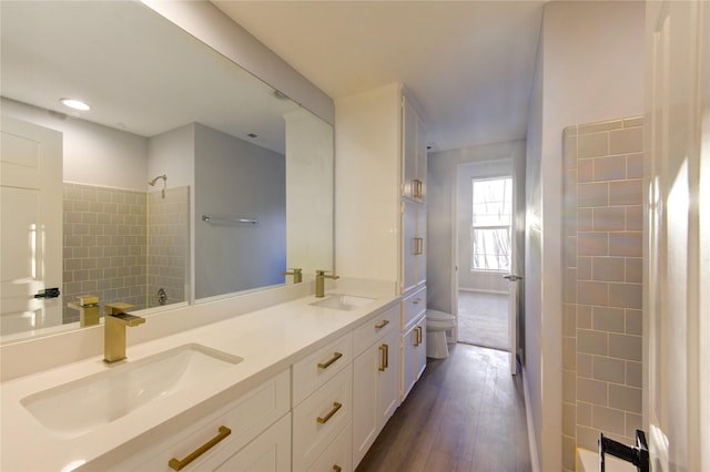 full bath with double vanity, shower / bathtub combination, a sink, and wood finished floors