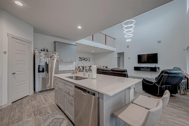 kitchen featuring appliances with stainless steel finishes, open floor plan, light countertops, light wood-style floors, and a sink