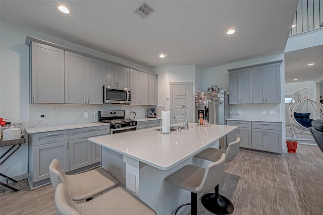 kitchen with a sink, appliances with stainless steel finishes, gray cabinets, and light wood-style floors