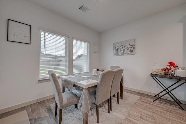 dining space featuring light wood finished floors, baseboards, and visible vents