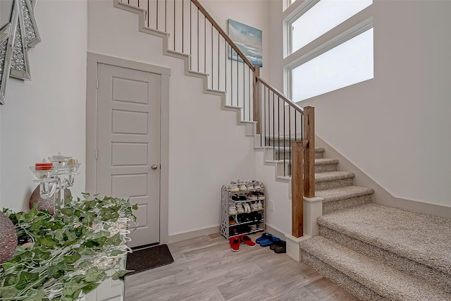 staircase featuring a high ceiling, wood finished floors, and baseboards