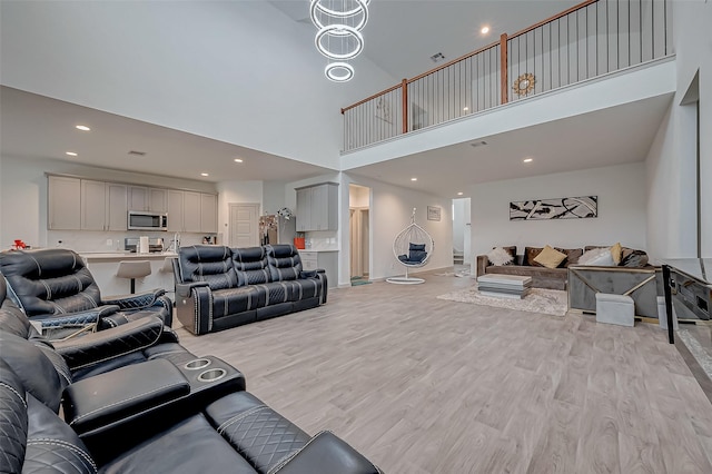 living room with light wood-type flooring, visible vents, a towering ceiling, and recessed lighting