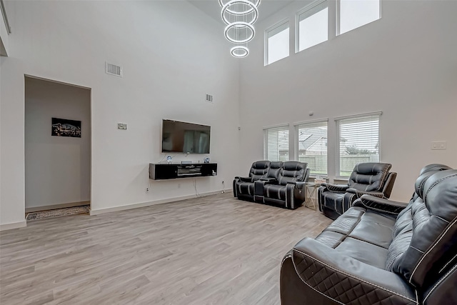 living area featuring baseboards, visible vents, a chandelier, and wood finished floors