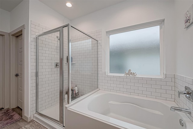 bathroom with a garden tub, a shower stall, and wood finished floors