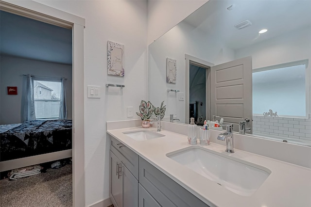 ensuite bathroom with a sink, double vanity, connected bathroom, and visible vents