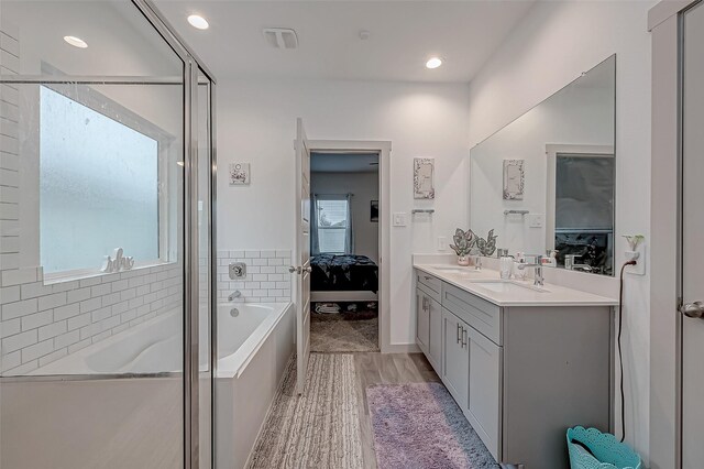 full bathroom with ensuite bathroom, a sink, a bath, double vanity, and a stall shower