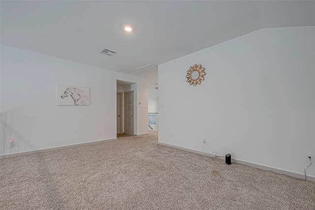 spare room with light carpet, baseboards, visible vents, and vaulted ceiling