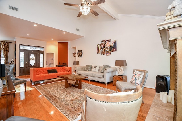 living area featuring visible vents, crown molding, light wood-type flooring, and a ceiling fan