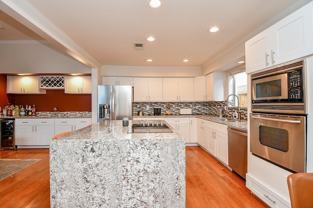 kitchen featuring visible vents, ornamental molding, a sink, wine cooler, and appliances with stainless steel finishes