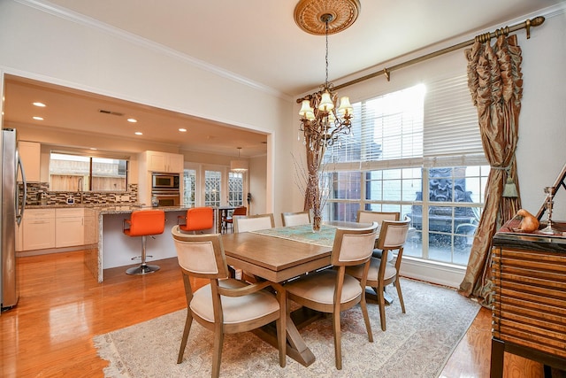 dining room with a wealth of natural light, visible vents, a notable chandelier, and ornamental molding