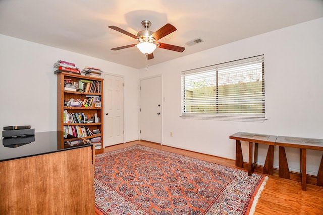 office area with light wood-type flooring, visible vents, baseboards, and ceiling fan