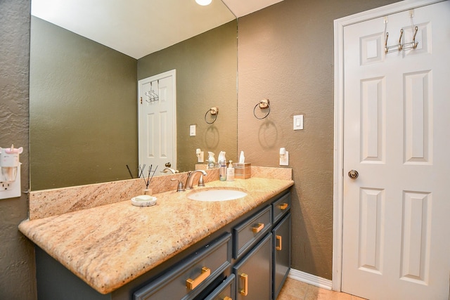 bathroom with vanity, baseboards, and a textured wall