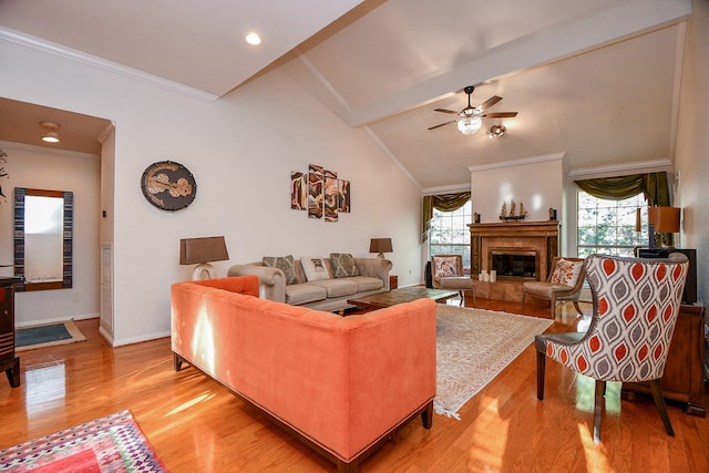 living area featuring lofted ceiling with beams, a fireplace, ornamental molding, ceiling fan, and light wood-type flooring