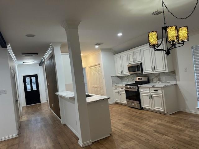 kitchen featuring stainless steel appliances, decorative backsplash, ornamental molding, dark wood-type flooring, and white cabinets