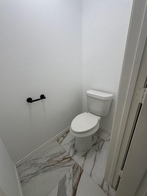 bathroom featuring marble finish floor, toilet, and baseboards