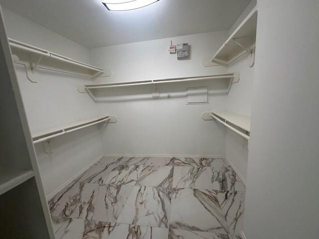 walk in closet featuring marble finish floor