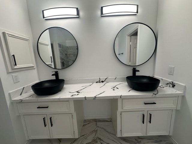 bathroom featuring marble finish floor, double vanity, and a sink