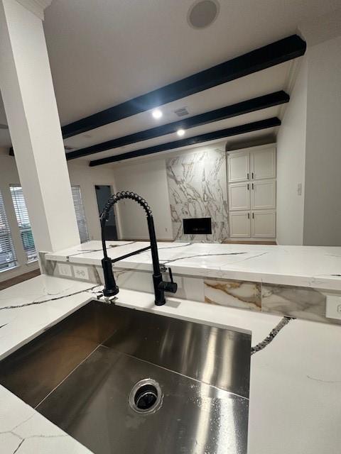 details with light stone counters, beam ceiling, and a sink