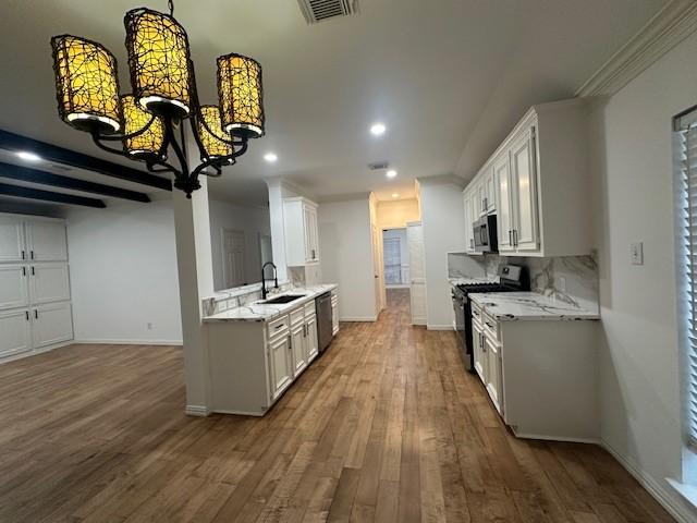 kitchen featuring dark wood-style floors, stainless steel appliances, visible vents, decorative backsplash, and a sink