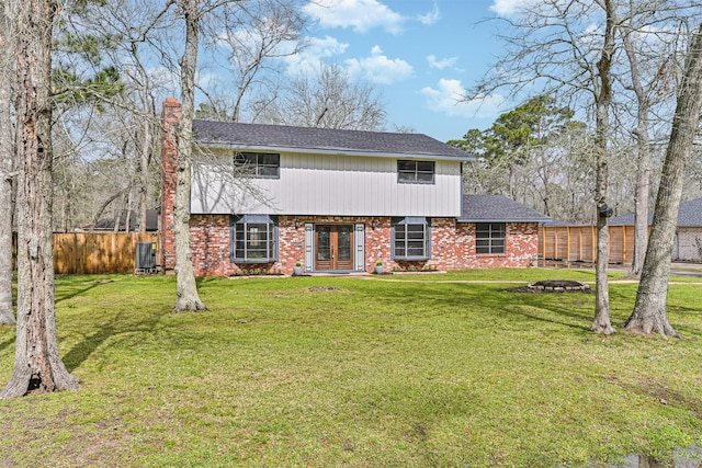 colonial inspired home with brick siding, a chimney, fence, french doors, and a front yard