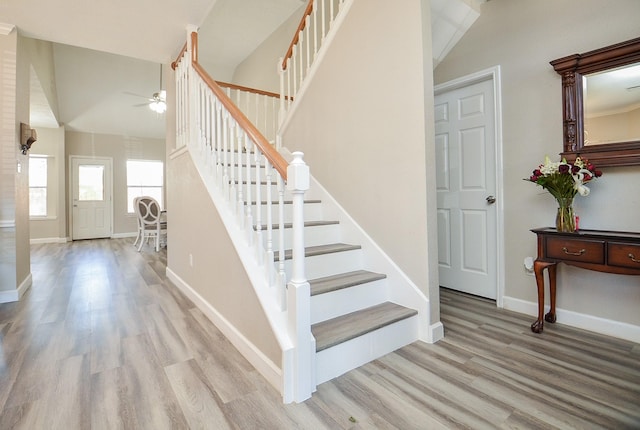 stairway with baseboards, vaulted ceiling, and wood finished floors