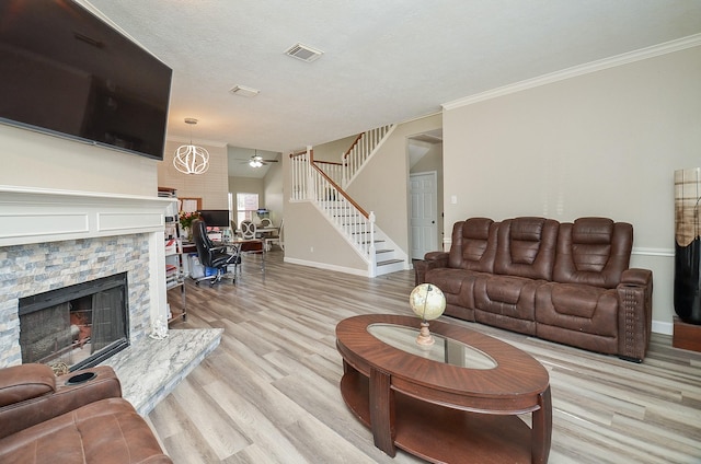 living room with light wood finished floors, baseboards, visible vents, stairway, and a fireplace