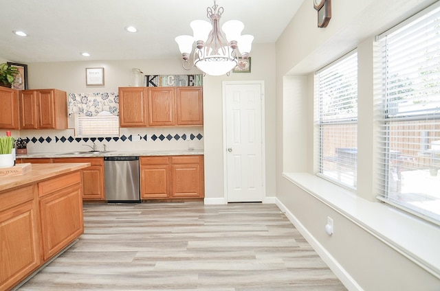 kitchen with tasteful backsplash, dishwasher, hanging light fixtures, light countertops, and a sink