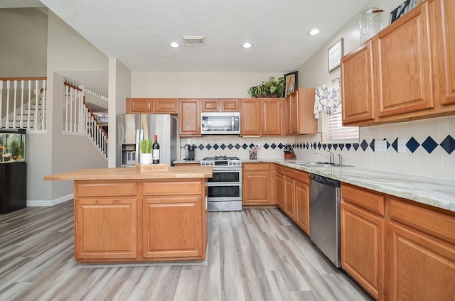 kitchen with visible vents, light wood-style flooring, appliances with stainless steel finishes, a center island, and a sink