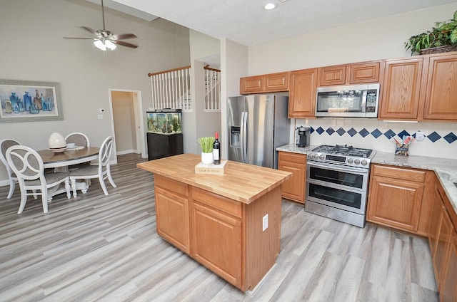 kitchen with appliances with stainless steel finishes, light wood-style floors, wooden counters, and tasteful backsplash