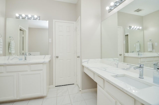 bathroom with two vanities, visible vents, a sink, and baseboards