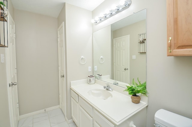 bathroom featuring baseboards, vanity, and toilet