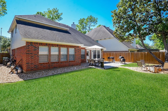 rear view of house with a patio, brick siding, fence, a lawn, and a chimney