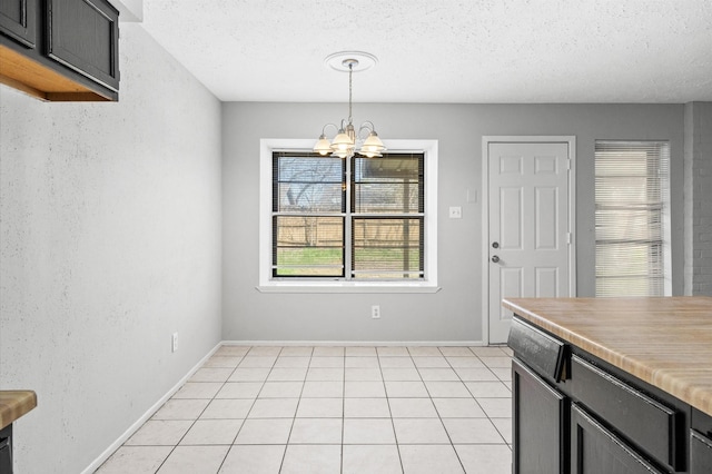 unfurnished dining area with light tile patterned floors, baseboards, a chandelier, and a textured ceiling