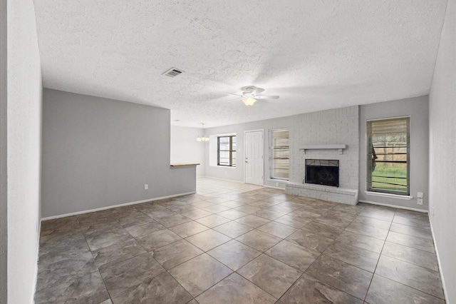 unfurnished living room with tile patterned flooring, a brick fireplace, visible vents, and ceiling fan with notable chandelier