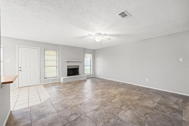 unfurnished living room with visible vents, baseboards, ceiling fan, a textured ceiling, and a fireplace