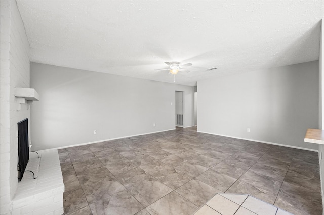 unfurnished living room featuring a brick fireplace, ceiling fan, baseboards, and a textured ceiling