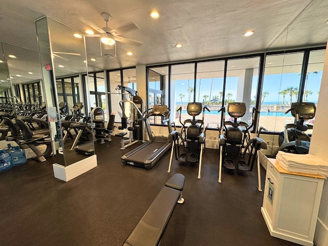 workout area with ceiling fan, expansive windows, a textured ceiling, and recessed lighting