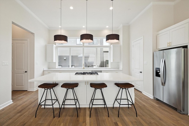 kitchen featuring crown molding, a breakfast bar, stainless steel refrigerator with ice dispenser, and white cabinets