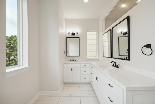 bathroom featuring double vanity, baseboards, a sink, and tile patterned floors